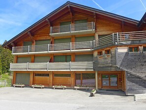 Ein mehrgeschossiges Holzgebäude mit Balkonen, großen Garagentoren und einer Treppe zu einer oberen Ebene.