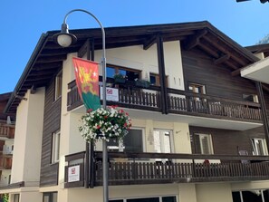 En byggnad med flera våningar, balkonger, en flagga och en blomkruka.