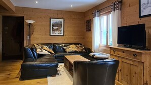 Una sala de estar acogedora con un conjunto de sofá, un televisor y paredes de madera.