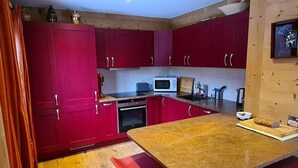 Una cocina compacta con armarios rojos, microondas, tostadora y encimera de madera.
