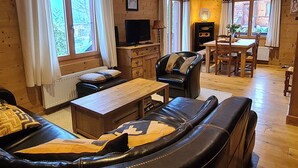 Una sala de estar acogedora con un sofá, una mesa de centro, un televisor y un comedor con una mesa y sillas.