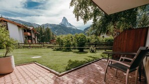 Un patio con vista sulle montagne, una recinzione in legno e una pianta in vaso.