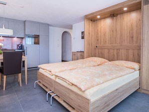 Une chambre moderne avec un lit en bois, un bureau et un coin cuisine.