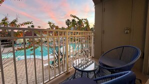 A balcony with a view of a swimming pool, two wicker chairs, and a table. - 207 Luxury 2-Unit Suite Pool | Universal & I-Drive (Orlando)