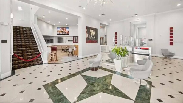 A modern hotel lobby with a staircase, a dining area, a reception desk, and a large chandelier. - 207 Luxury 2-Unit Suite Pool | Universal & I-Drive (Orlando)