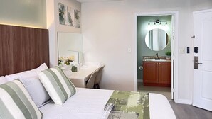 A hotel room with a bed, a desk, a mirror, and a bathroom visible through an open door. - 207 Luxury 2-Unit Suite Pool | Universal & I-Drive (Orlando)