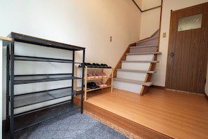 A staircase with a wooden finish, a shoe rack with shoes, and a door with a glass panel. - White Dream Lodge Furano (Furano-shi /Kitanomine-cho)