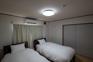 A hotel room with two single beds, an air conditioning unit, a wardrobe, and a curtain. - White Dream Lodge Furano (Furano-shi /Kitanomine-cho)