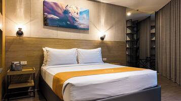 Ein Hotelzimmer mit Bett, Nachttisch, Lampe, Kunstwerken und Blick nach draußen.