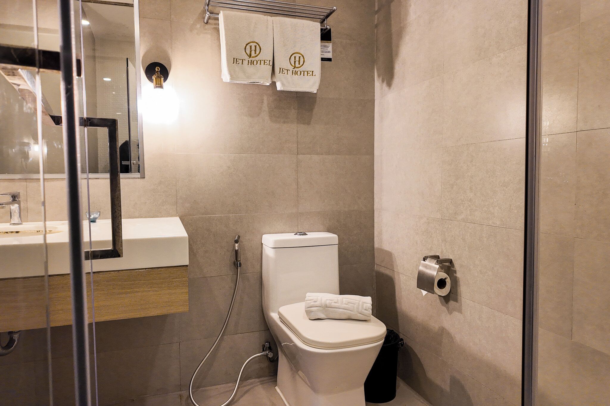 A modern bathroom with a toilet, bidet, and a glass shower enclosure.