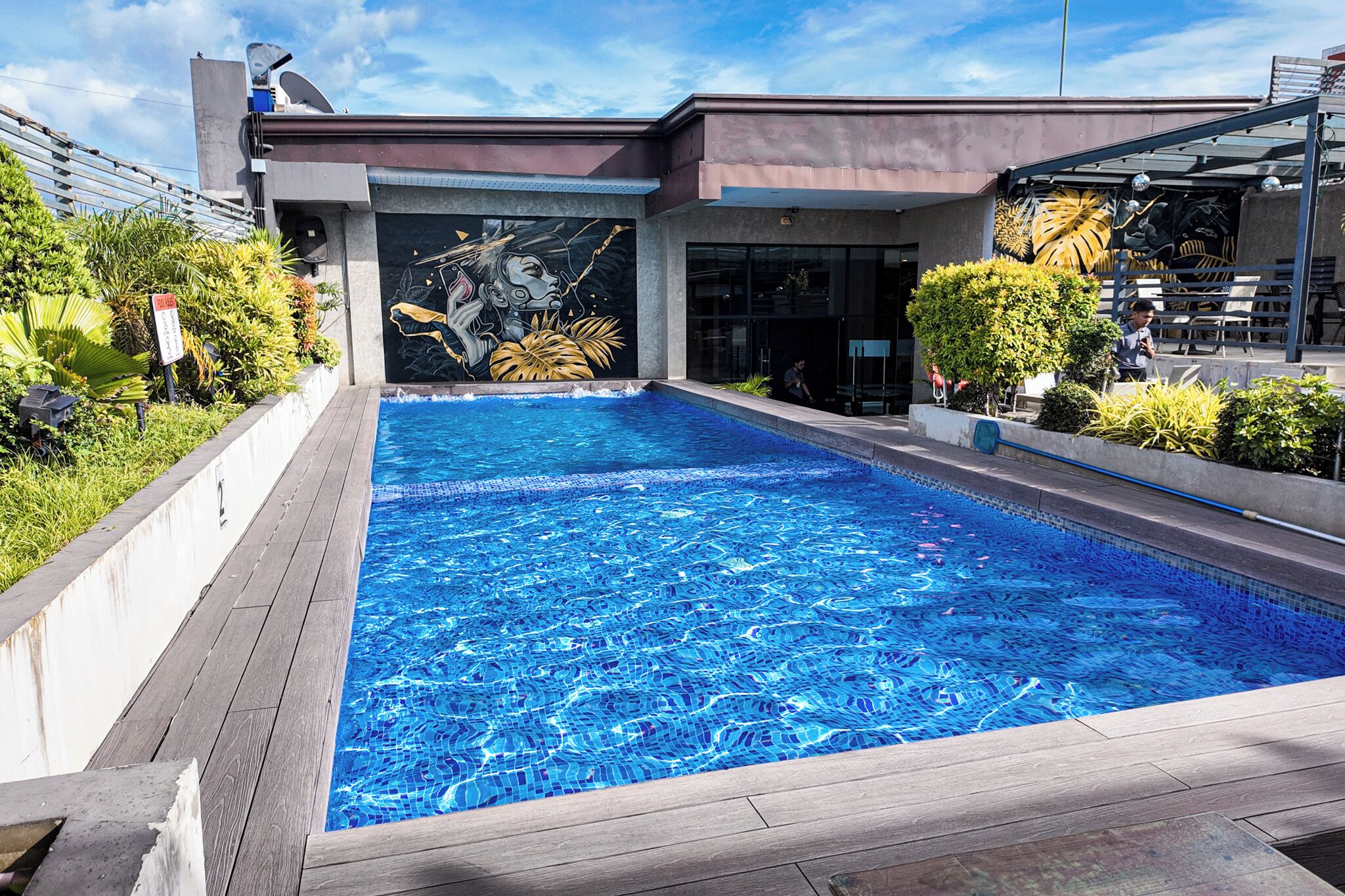 A swimming pool with a modern building in the background, surrounded by greenery.