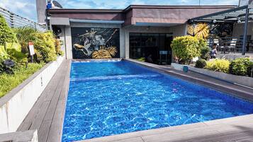 A swimming pool with a modern building in the background, surrounded by greenery.
