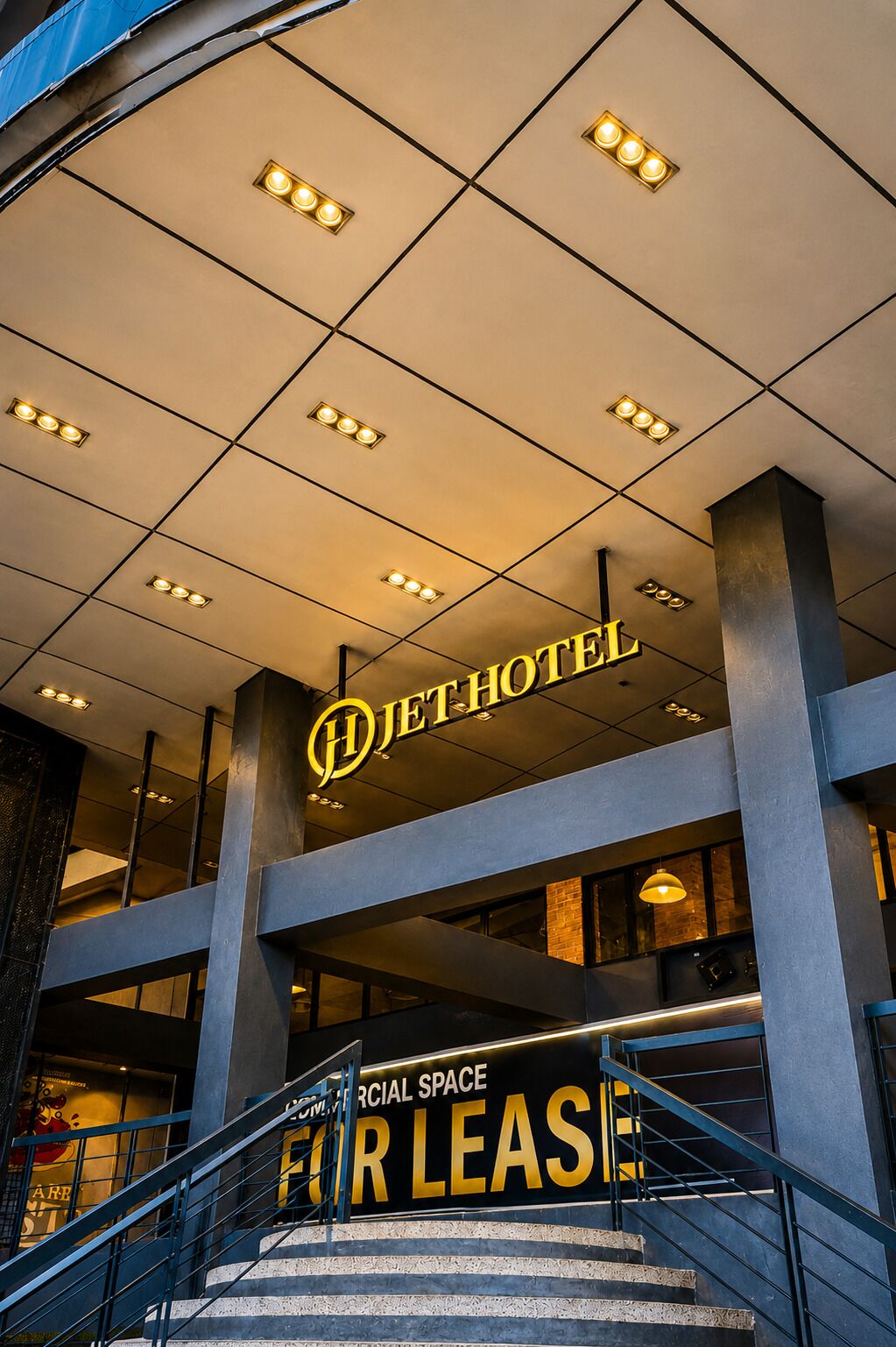 L’entrée d’un hôtel, avec une enseigne indiquant « JETHOTEL » et, en dessous, une autre enseigne indiquant « À LOUER ».