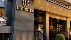 Entrada de hotel moderna con un letrero llamativo, una escalera que conduce al lobby y una fachada bien iluminada.