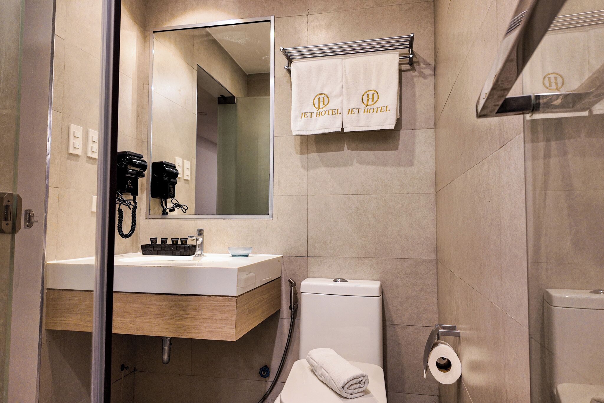 A modern bathroom with a sink, mirror, towel rack, and toilet.