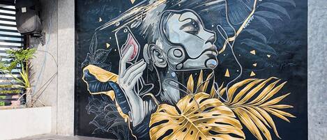 A swimming pool with a mural of a person holding a smartphone, surrounded by tropical foliage.