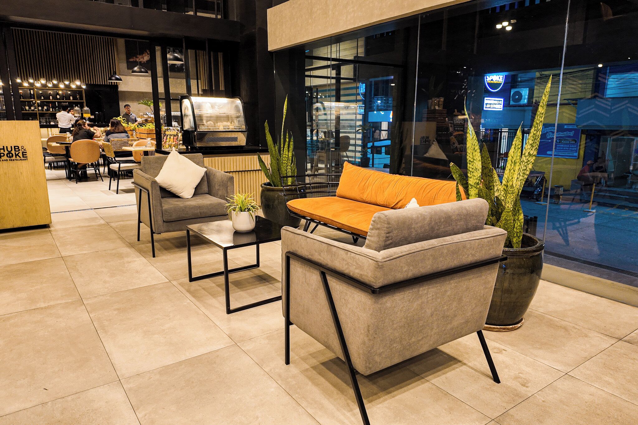 Et moderne loungeområde med sofaer, et sofabord og potteplanter.