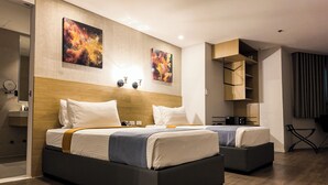 Habitación de hotel moderna con dos camas, cabecero de madera, una obra de arte en la pared, un escritorio y una silla.