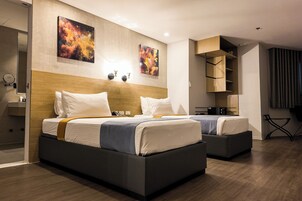 Habitación de hotel moderna con dos camas, cabecero de madera, una obra de arte en la pared, un escritorio y una silla.