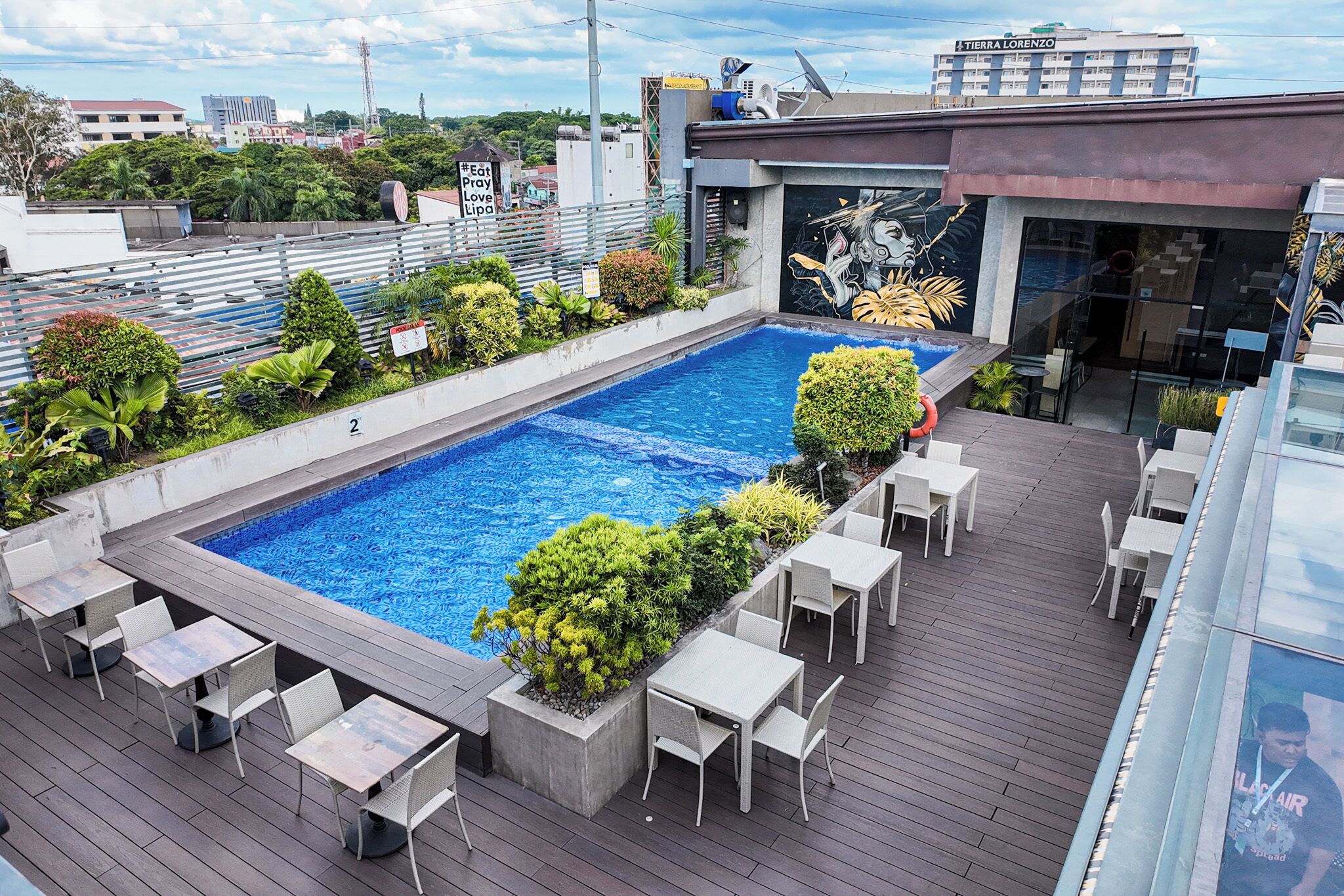 A rooftop pool with surrounding seating and a mural.