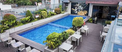 A rooftop pool with surrounding seating and a mural.
