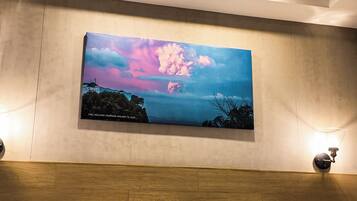 A hotel room with a bed, a nightstand, a wall-mounted painting, and a ceiling light fixture.