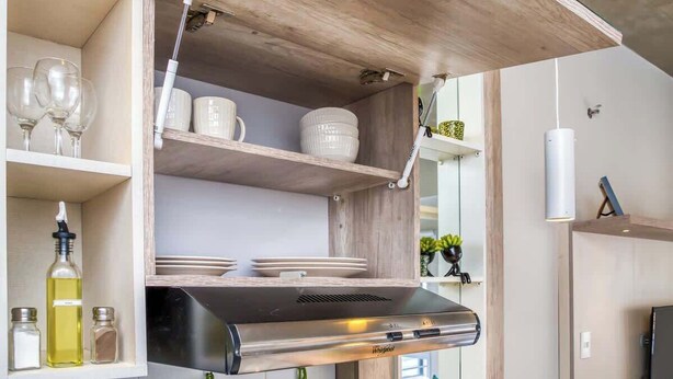 A kitchen with a built-in range hood, shelves with dishes, and a hanging light fixture. - Corporate Stays Zuba III - 604 (Fernando de la Mora)