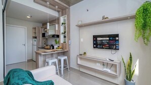 A modern living room with a sofa, a TV mounted on the wall, a kitchen area, and a potted plant. - Corporate Stays Zuba III - 604 (Fernando de la Mora)