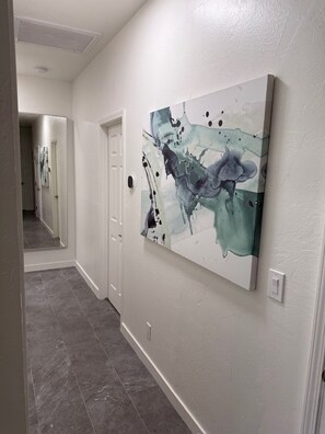Ein Flur mit einem großen, abstrakten Gemälde, einer weißen Tür und einem Lichtschalter an der Wand.