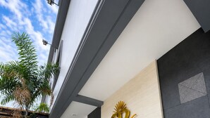 Entrada de hotel com design moderno, exibindo o logotipo e o nome na fachada.
