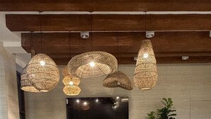 Uma sala de estar moderna com móveis de vime, uma TV de tela plana e luminárias de vime suspensas.