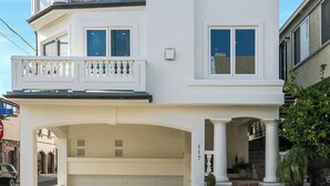 Ein zweistöckiges Haus mit Garage, Balkon und kleiner Veranda.