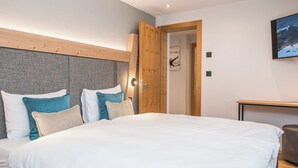 Une chambre à coucher moderne avec un grand lit, une tête de lit en bois et un tableau accroché au mur.