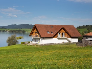 A house with a sloped roof, a balcony, and a view of a lake and mountains. - Ferienhof am See – Willerzell, (Willerzell), by Interhome (Willerzell)