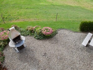 A gravel patio with a chair and a bench, surrounded by a hedge and flowering plants. - Ferienhof am See – Willerzell, (Willerzell), by Interhome (Willerzell)