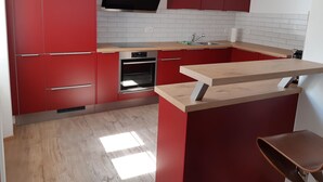 Una cocina moderna con armarios rojos, horno empotrado y encimera de madera.