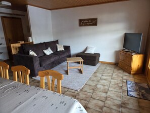 A furnished living room with a sofa, chairs, a coffee table, a television, and a wooden cabinet. - Oeillet 4, (Champoussin), by Interhome (Les Crosets)