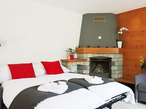 Ein Schlafzimmer mit einem Bett, roten und weißen Kissen, einem Kamin und einer Blumentopf-Pflanze.