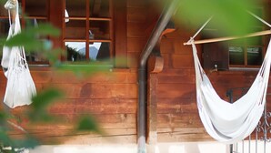 Una cabaña de madera con una hamaca y un bolso colgante.