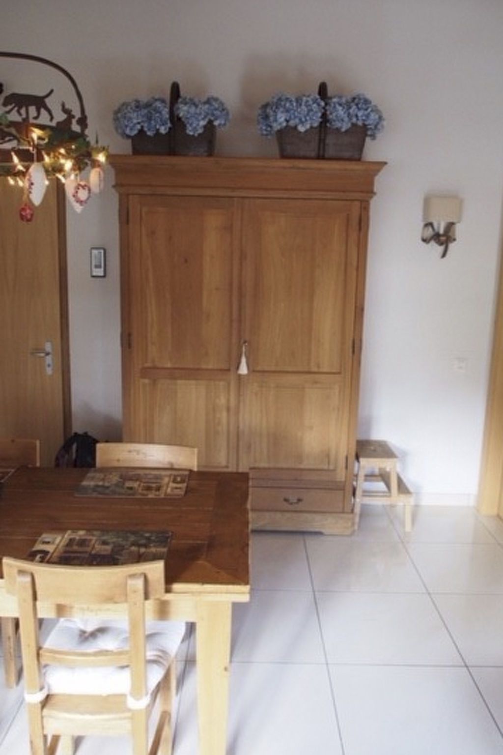 Un comedor con una mesa de madera, sillas y un mueble con objetos decorativos.