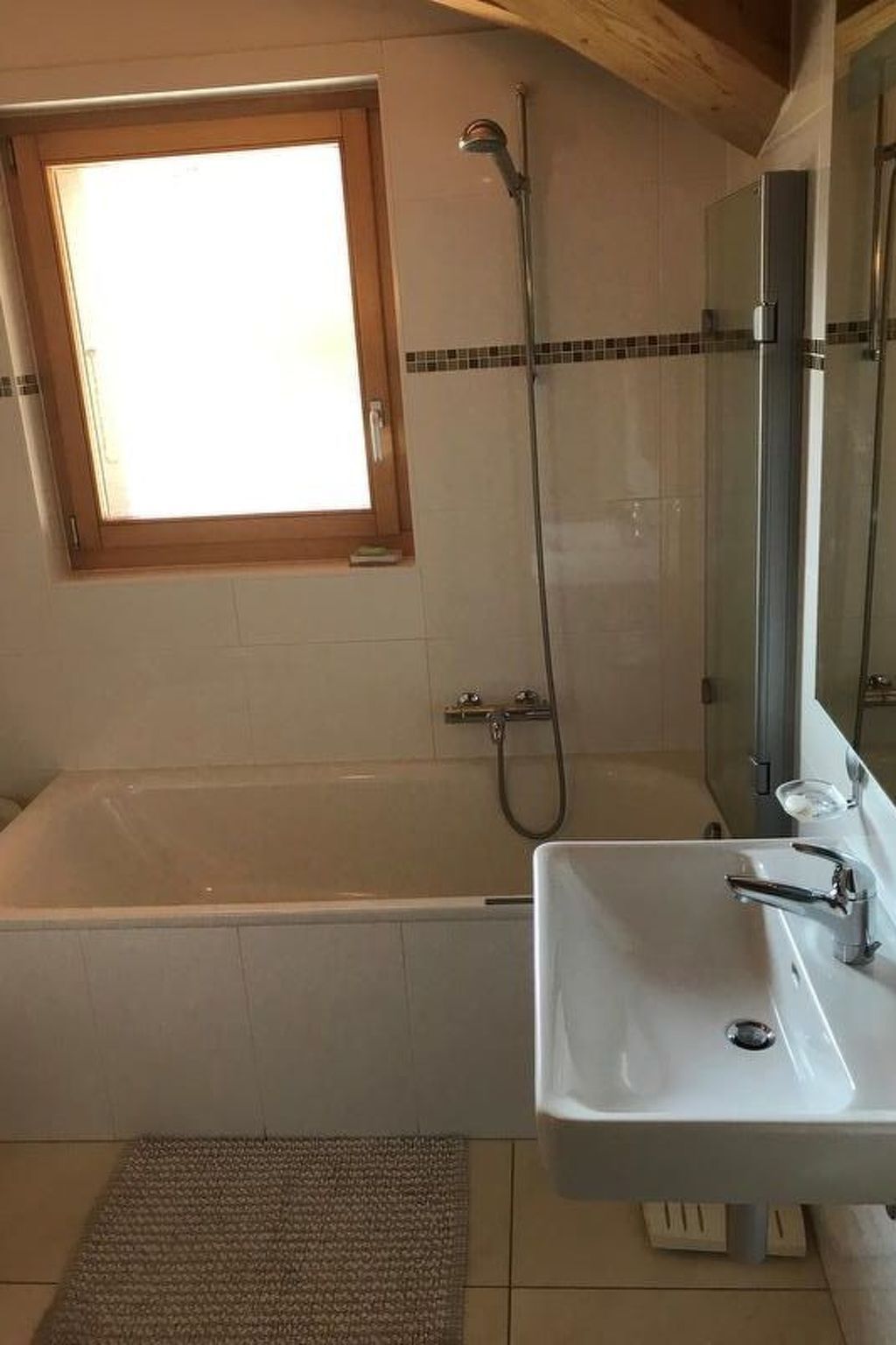 Une salle de bain avec une baignoire, une douche, un lavabo et une fenêtre.