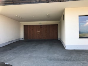 Un garaje con piso de concreto, puerta de madera y ventana con vista al cielo.