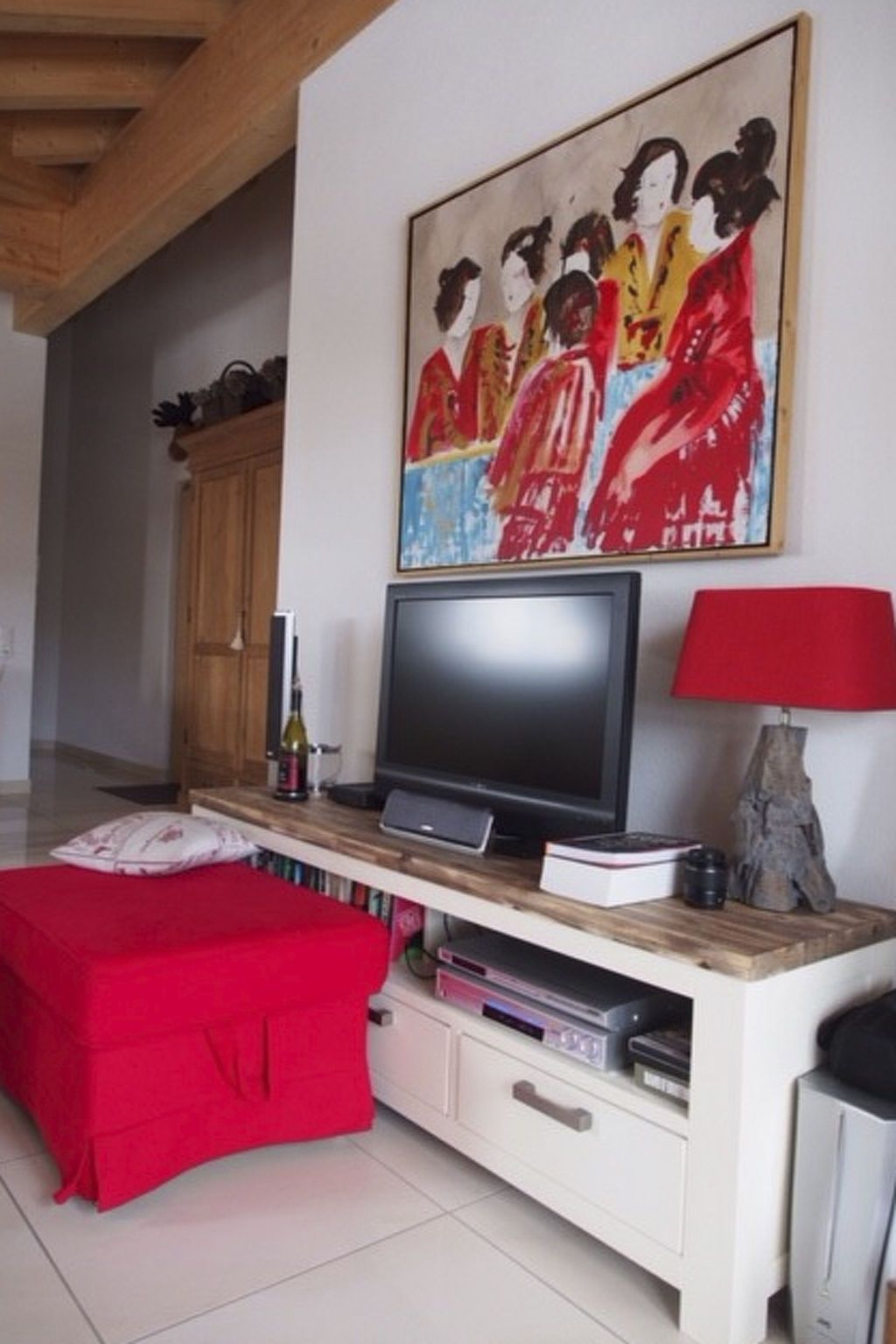 A living room with a flat-screen TV, a red lamp, and a painting on the wall.