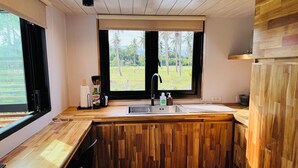 Una cocina con encimera de madera, un lavamanos y una ventana con vista a palmeras.