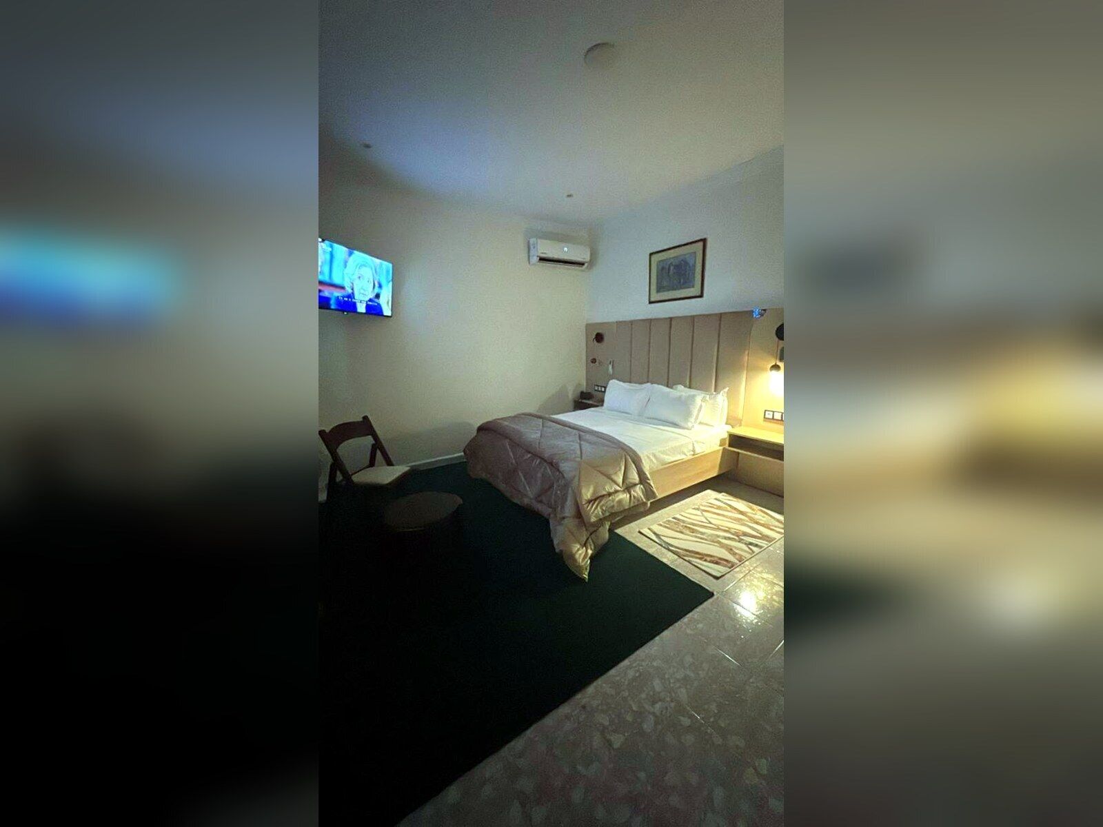Ein Hotelzimmer mit einem Bett, einem Sessel, einem Fernseher und einer Klimaanlage.