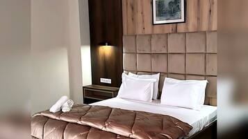 Een hotelkamer met een bed, nachtkastje, een wandlamp en een ingelijste foto.