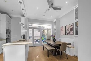 Eine moderne Küche mit weißen Schränken, einem Essbereich mit einer Bank und einem Deckenventilator.