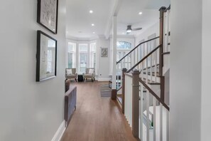 A hallway with a staircase, a seating area with chairs, and a ceiling fan. - Gold Coast Pristine 5BR - 3.5BA - Patio - Parking (Chicago)