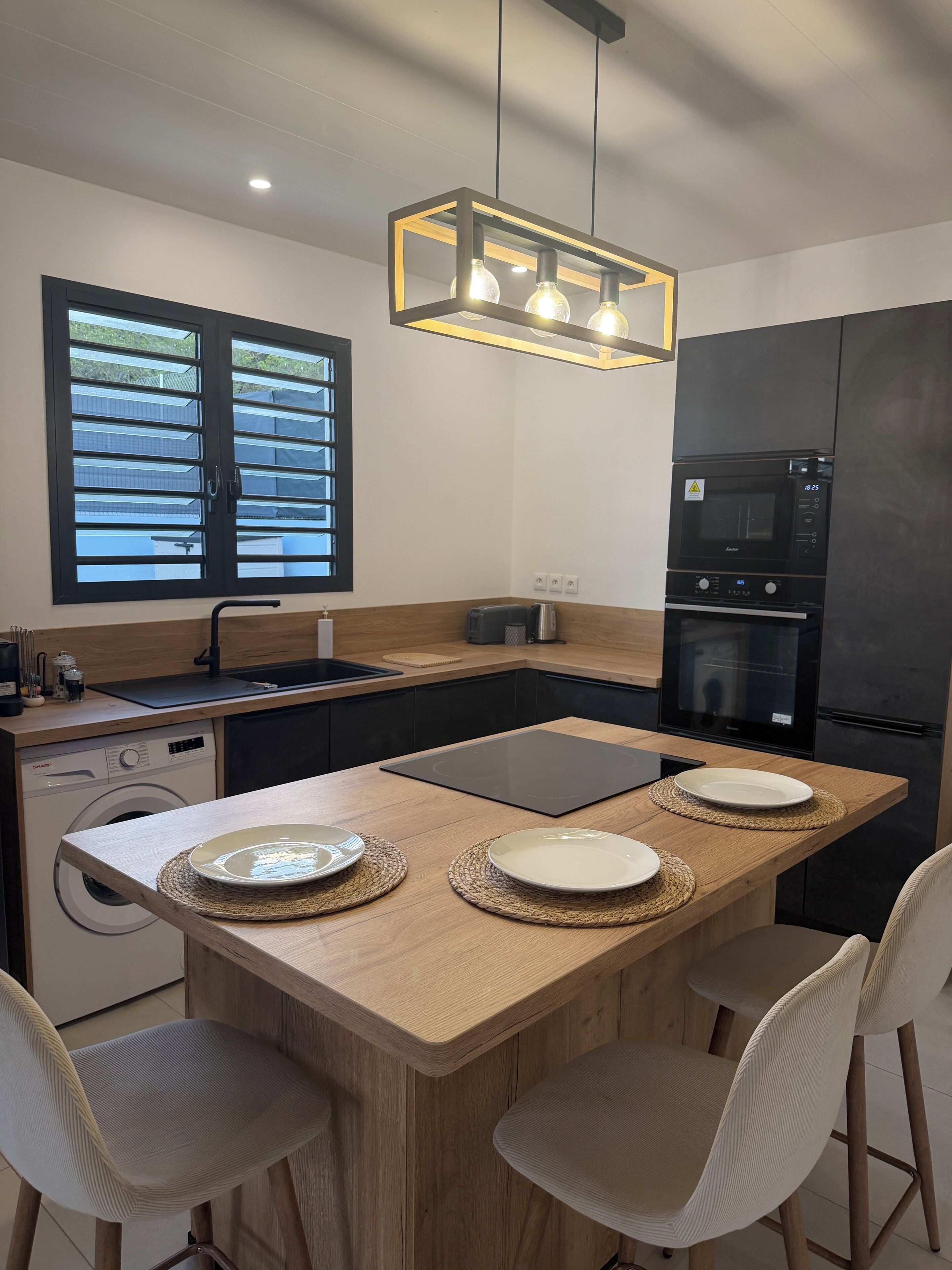 A modern kitchen with a wooden island, built-in appliances, and a window with blinds.