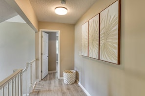 A hallway with a wooden floor, a white door, and a wall-mounted decorative panel. - Short Walk to the Beach, Screened Porch, Renovated Home, 4 miles to Downtown, $300 in Free Tickets! (St. Augustine)